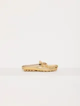 Mocasín tipo mule (destalonado) de cuero vacuno flor con textura croco, color dorado metalizado. Presenta un detalle metálico en forma de corazón sobre el empeine y suela de goma con relieve.