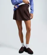 Short pollera de estilo sastre con patrón de rayas finas, diseño estructurado con pliegues delanteros y hebilla lateral ajustable.