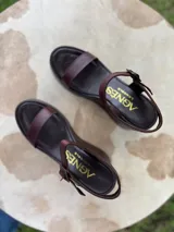 Sandalias de cuero color marrón chocolate con plataforma y taco corrido. Tira ancha sobre los dedos y tira al tobillo con hebilla dorada.