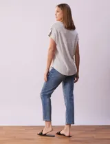 Remera gris a rayas horizontales blancas, con cuello a la base y escote en V. Manga corta con presilla y botón.