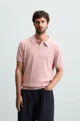 Polo de punto canalé color rosado, de corte regular fit, con cuello solapa y cierre frontal de botonadura. Manga corta y acabados en rib.