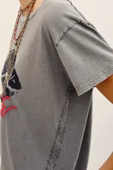 Remera de algodón gris con efecto acid wash, mangas cortas y estampa frontal de labios oscuros con la palabra "Kiss" en rojo.