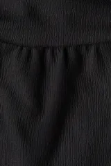 Pantalón negro de corte holgado en tejido de punto con efecto arrugado. Presenta una cintura ancha fruncida con elástico oculto y piernas globo con bajos elásticos.