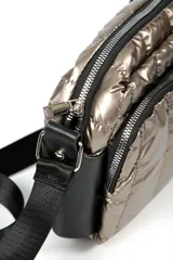 Cartera tipo bandolera de diseño acolchado en color plateado metalizado. Cuenta con dos compartimentos principales con cierre, detalles en negro y correa ajustable extraíble.