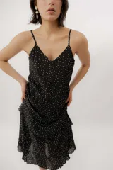 Vestido midi negro con estampado de lunares blancos, escote en V, breteles finos y diseño con volados en capas.