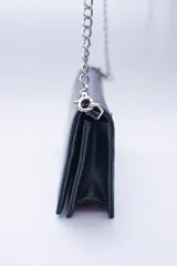 Cartera negra con textura símil cocodrilo y cadena metálica plateada.