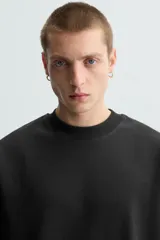 Sudadera de manga corta color marrón oscuro, con cuello redondo y bajo acabado en rib. Presenta un corte relajado y holgado (boxy fit).