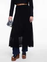 Falda larga negra de punto con sutil brillo de lurex. Presenta un corte evasé y cintura plana, con un ruedo ligeramente transparente.