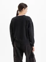 Buzo de cuello redondo y mangas largas, con calce amplio y largo a la cadera. Presenta una estampa frontal con diseño de esquiadora y la frase 'Après Ski', junto con un logo bordado en la espalda.