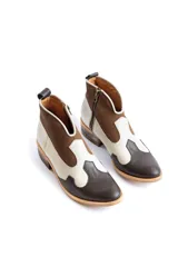 Botinetas estilo western de caña baja, confeccionadas en una combinación de cuero liso y gamuza en tonos marrón oscuro, marrón medio y crema. Presentan cierre lateral, taco bajo cuadrado y diseño con recortes característicos del estilo cowboy.