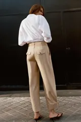 Pantalón de tiro bajo con pinzas delanteras, bolsillos frontales y bolsillos de plastrón con solapa en la parte trasera. Presenta una pernera ancha y bajo con botones a presión para ajuste.