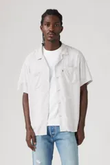 Camisa de manga corta con estampado abstracto en tonos grises y blancos, cuello tipo camp y cierre frontal con botones.