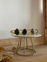 Gargantilla rígida de bronce con diseño de doble aro y piedras de nácar oscuro engarzadas en el centro.