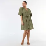 Vestido corto verde militar con bordado inglés, escote en V con botones frontales, mangas cortas y lazo ajustable en la cintura.