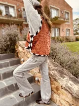 Chaleco color crema con ribete amarillo, de corte recto y sin mangas.