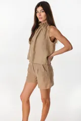 Blusa de lino italiano color marrón oscuro, con corte en línea A, hombros descubiertos, escote halter con frunces y volado en el cuello.