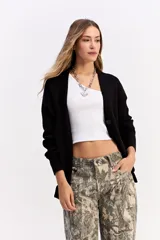 Saco de punto color crema con escote en V, cierre frontal con botones y bolsillos delanteros. Presenta un diseño de calce relajado con estructura marcada.