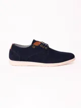 Zapatos acordonados de estilo urbano en material efecto gamuza color azul marino, con suela blanca y detalles en cuero sintético marrón en la lengüeta y el talón.