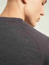 Camiseta deportiva de manga corta con diseño de corte ranglán, confeccionada en tejido técnico con textura jaspeada. Presenta cuello redondo y dobladillo ligeramente curvo.