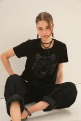 Remera de algodón color negro, con cuello redondo y mangas cortas. Presenta un estampado frontal de un tigre en tonos oscuros y texturas sutiles.