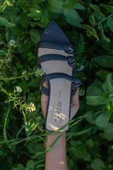 Sandalias negras de cuero con punta fina y tiras finas con nudos.