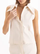 Camisa sin mangas de color marrón oscuro, confeccionada en tejido de punto, con cuello camisero clásico y cierre frontal de botones.