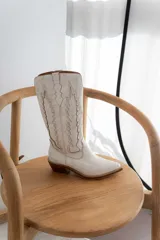 Bota de cuero color marrón con bordado decorativo en el caño, taco bajo y punta fina.