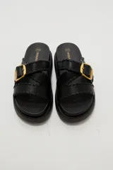 Sandalias planas de eco cuero color bordó, con tiras cruzadas y hebilla metálica dorada.