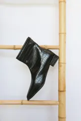 Botinetas negras con textura símil cocodrilo, de corte clásico, con cierre lateral y taco cuadrado bajo.