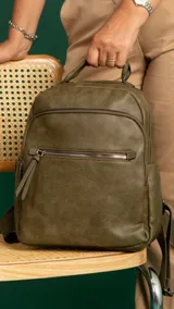 Mochila urbana color beige de símil cuero, con dos bolsillos frontales, bolsillo principal de gran capacidad con dos bolsillos internos con cierre y uno abierto, bolsillos laterales abiertos, asa de mano y correas regulables en galón.