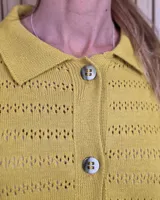 Cardigan de punto color marrón tostado, con cuello camisero, cierre frontal con botones y diseño de rayas sutiles en el tejido. Presenta mangas largas con puños elásticos y corte recto.