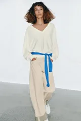 Jersey de punto color blanco crema, con escote en pico, manga larga y sisa ancha terminada en puño.