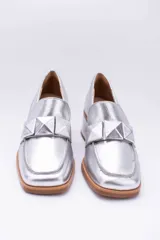 Mocasines plateados de cuero con aplique geométrico al tono y taco cuadrado.