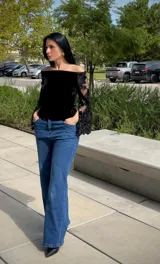 Blusa negra de terciopelo con escote bote y mangas largas acampanadas de encaje con detalles de lentejuelas.