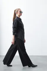 Jean wide leg de color negro con silueta amplia y caída fluida. Presenta detalles de tachas aplicadas que recorren el diseño en forma de ondas. Confeccionado en denim de algodón.