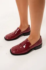 Mocasín de cuero charol color cereza con diseño enrejillado en la capellada, horma cuadrada, plataforma delantera y taco bajo.