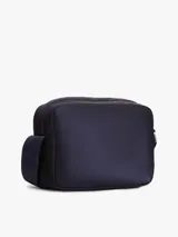Morral cruzado Tommy Hilfiger de diseño práctico y funcional, confeccionado en poliamida reciclada azul marino con forro de poliéster. Cuenta con un compartimento principal, bolsillo exterior con cierre de cremallera, correa ajustable extraíble y detalles distintivos con la bandera metalizada de la marca.