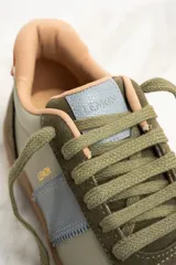 Zapatillas bajas de cuero color verde oliva, beige y celeste con suela marrón.