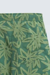 Bañador largo de tejido técnico color verde oscuro con estampado de flores en tono verde más claro. Presenta cintura elástica ajustable con cordón, bolsillos laterales y un bolsillo trasero de plastrón.