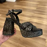 Sandalias negras con plataforma y taco cuadrado, tiras cruzadas en el empeine y pulsera con hebilla al tobillo.