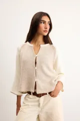 Saco de algodón tejido, color beige con mangas y detalles en blanco, escote en V y cierre frontal de botones.