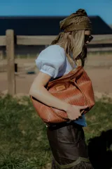 Cartera tipo canasto color marrón, hecha en 100% cuero con diseño tejido. Tiene bolsillo interno, porta llaves y cierre.