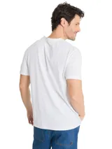 Remera Caterpillar blanca de manga corta y cuello redondo, con estampa fotográfica y gráfica en el pecho con texto institucional y de la marca.