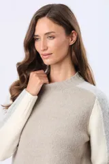 Buzo tejido de punto con cuello redondo y mangas largas. Presenta un diseño de bloques de color con franjas en tonos contrastantes a lo largo de las mangas y un detalle de etiqueta de cuero en el ruedo.