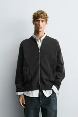 Chaqueta tipo bomber de punto compacto con efecto lavado, cuello subido, manga larga y cierre frontal con cremallera. Presenta bolsillos de vivo en la cadera y acabados en rib.