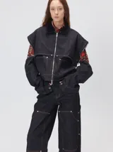 Campera de denim a rayas verticales con cuello de pana en color bordó. Presenta cierre frontal, mangas desmontables con cierre en los hombros, canesú en el pecho y bolsillos de parche cuadrados.