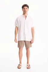 Camisa de lino de manga corta, color blanco, con cuello mao y cierre frontal de botones.