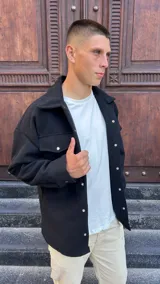 Chaqueta tipo sobrecamisa de paño en color negro, con corte oversize, cuello clásico, cierre frontal con botones metálicos a presión y bolsillos frontales con solapa.