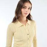 Cárdigan de punto fino color amarillo pastel, con cuello tipo polo, manga larga y cierre frontal de botones metálicos.
