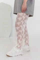 Pantalón acampanado de encaje blanco con estampado floral, de tiro alto y corte ancho.